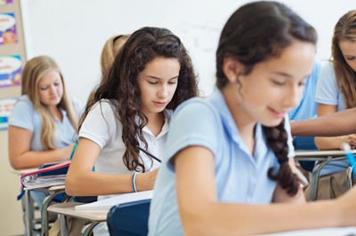 Young girls sit at desks in a school setting
