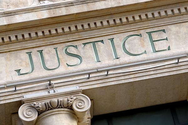 An exterior of a law building with the word "justice" enscribed on it